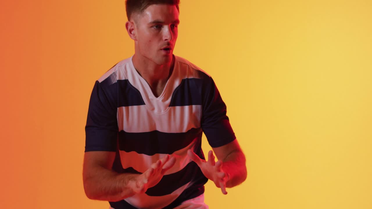 오렌지색 조명 위에서 럭비 공을 잡는 백인 남성 럭비 선수