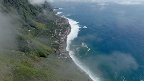 nubes finas y brumosas cuelgan bajas en las verdes montañas que se elevan sobre la ciudad costera de madeira, portugal.