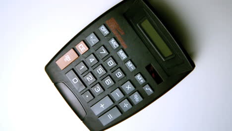 calculadora negra cayendo sobre una superficie blanca
