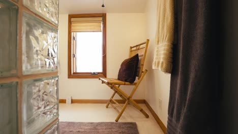 push in shot of a wooden chair with a pillow on top in the bathroom of a home