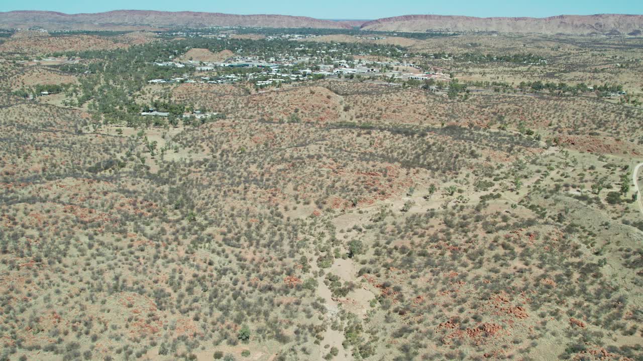 Aerial view of the dry river bed of the Charles River, with the town of Alice Springs, Mparntwe, in the distance. Northern Territory, Australia. August 2022.
