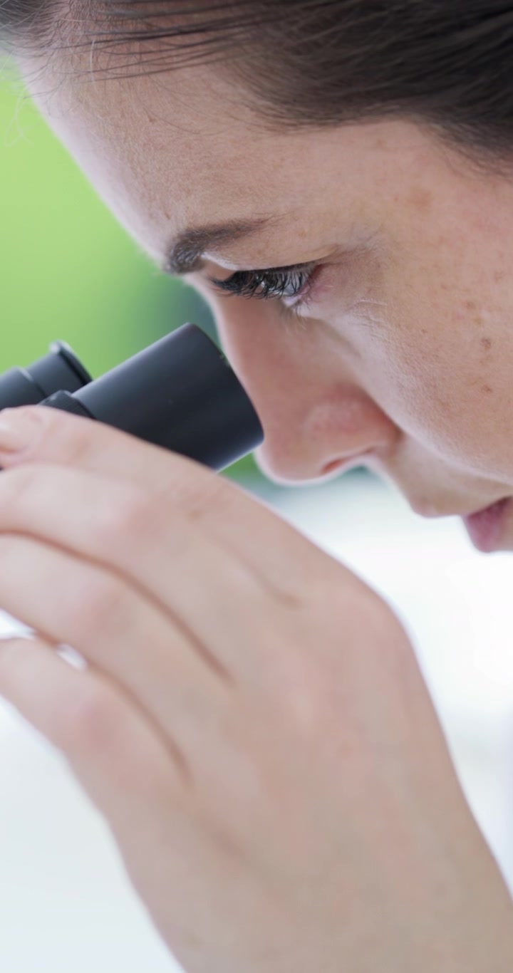 Scienziato che Esamina Vetrini al Microscopio in Laboratorio