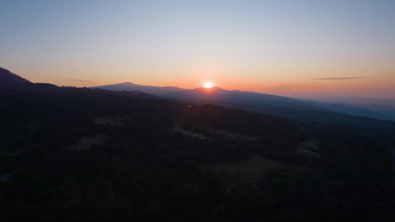 hiperlapso de adelante hacia atrás al amanecer, sobre montañas en méxico, con vista al sol
