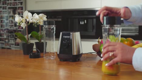 Jar-with-freshly-cut-fruit,-hand-move-it-to-mixer-to-blend-into-smoothie,-medium-shot