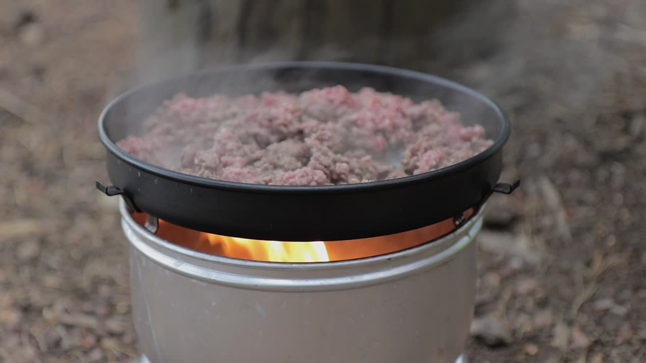 carne picada cocinada en una sartén encima de una estufa de camping, tiro estacionario