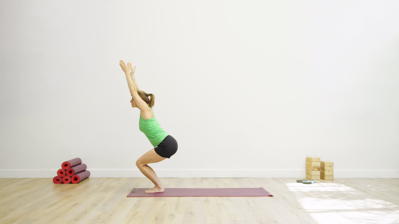 Frau praktiziert die Stuhl-Pose im Yoga in einem hellen Studio.