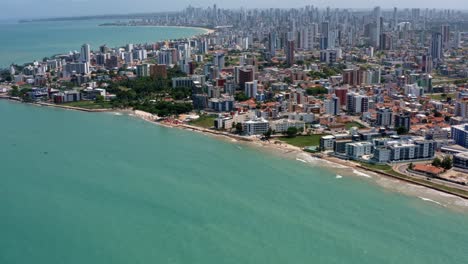 tilt up aerial wide shot of the tropical capital of joao pessoa from intermares beach in cabedelo, brazil with skyscrapers along the coastline in the state of paraiba on a warm sunny summer day