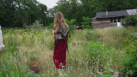 hermosa mujer fuera de la red hippie ecoconsciente caminando por jardines salvajes junto a la yurta en la ecoaldea