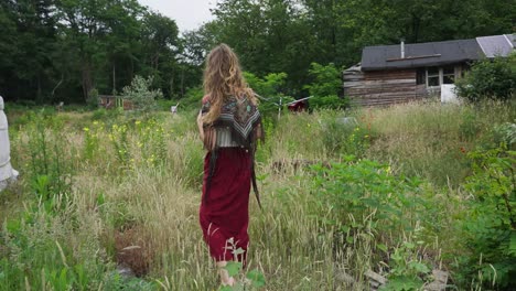 beautiful off grid woman female eco conscious hippie walking through wild gardens next to yurt in ecovillage