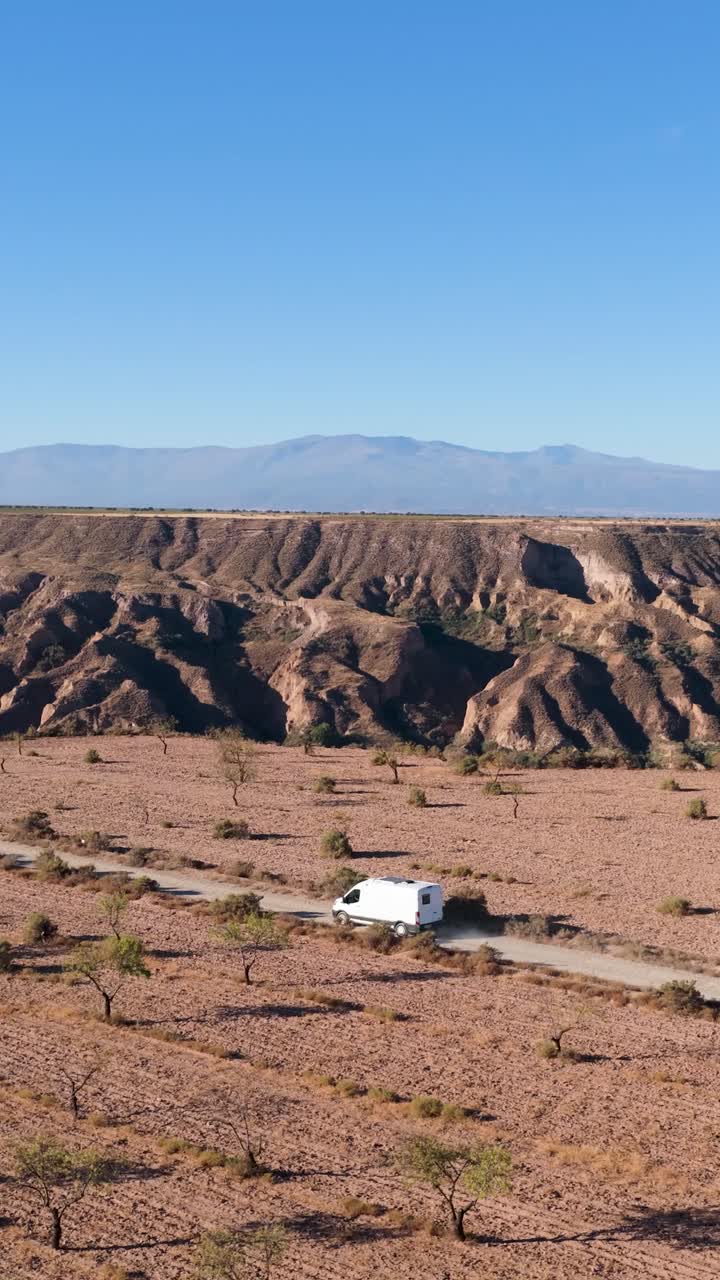Vista aerea di un furgone bianco che attraversa un paesaggio di canyon arido