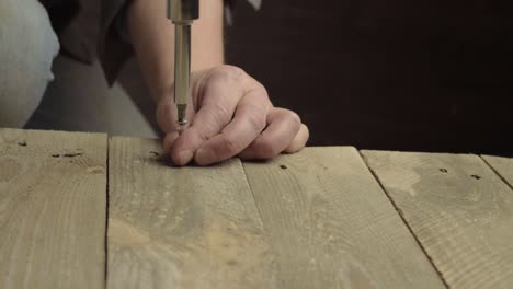 hand mit einem manuellen schraubendreher, um die schraube im holz zu befestigen