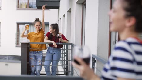 handheld video of three friends having home party on balcony