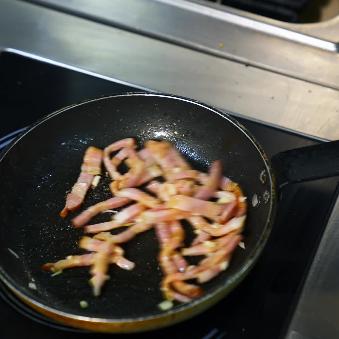 Cooking bacon for breakfast. Chef turns crispy bacon in frying pan. Ingredients for burger. Close up