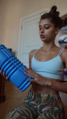 mujer que usa un rodillo de espuma para hacerse un masaje
