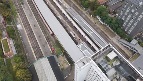 orbital aerial view of ealing broadway station's rail infrastructure with departing train in dynamic motion, london, uk, october 2024