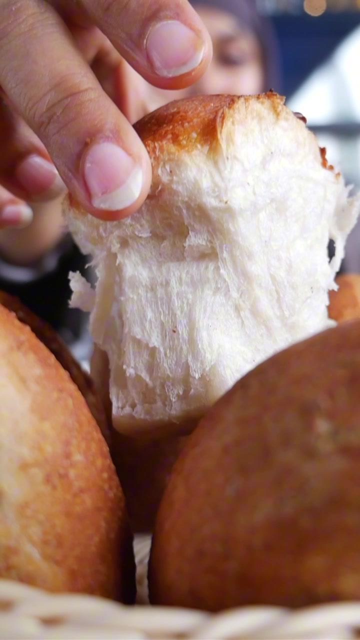 Woman in Hijab Tearing Fresh Bread Roll in a Cafe