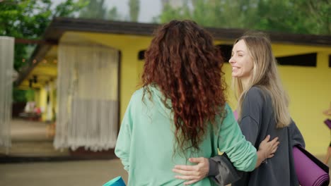 women met and go together for exercise holding mats for yoga