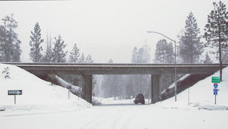 a car sits underneath an empty overpass to get out of a snowstorm in the early morning