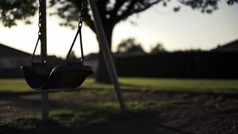 a serene evening at the playground: a swing gently sways under the setting sun, capturing the essence of nostalgia and outdoor playfulness