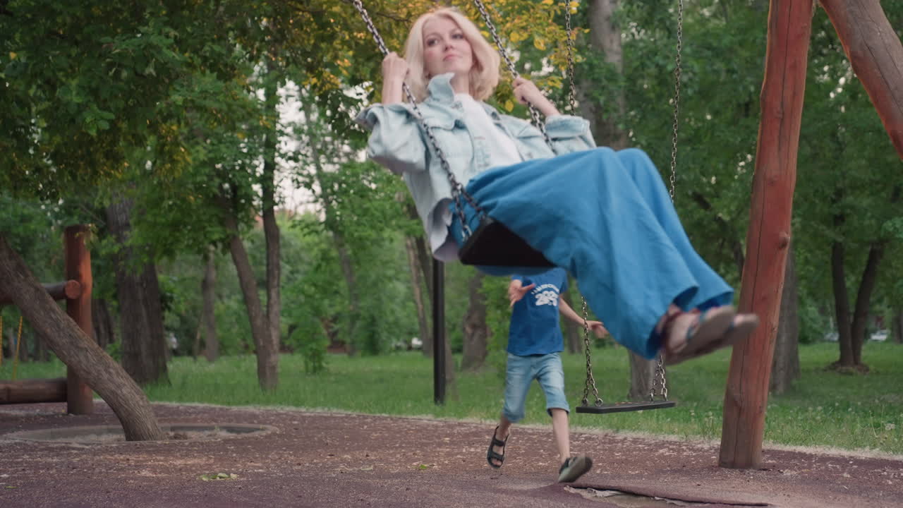 elegant lady seated on swing bench in quiet park at dusk holds chains and gazes thoughtfully as soft ambient light filters through trees and child runs past capturing serene reflective moment