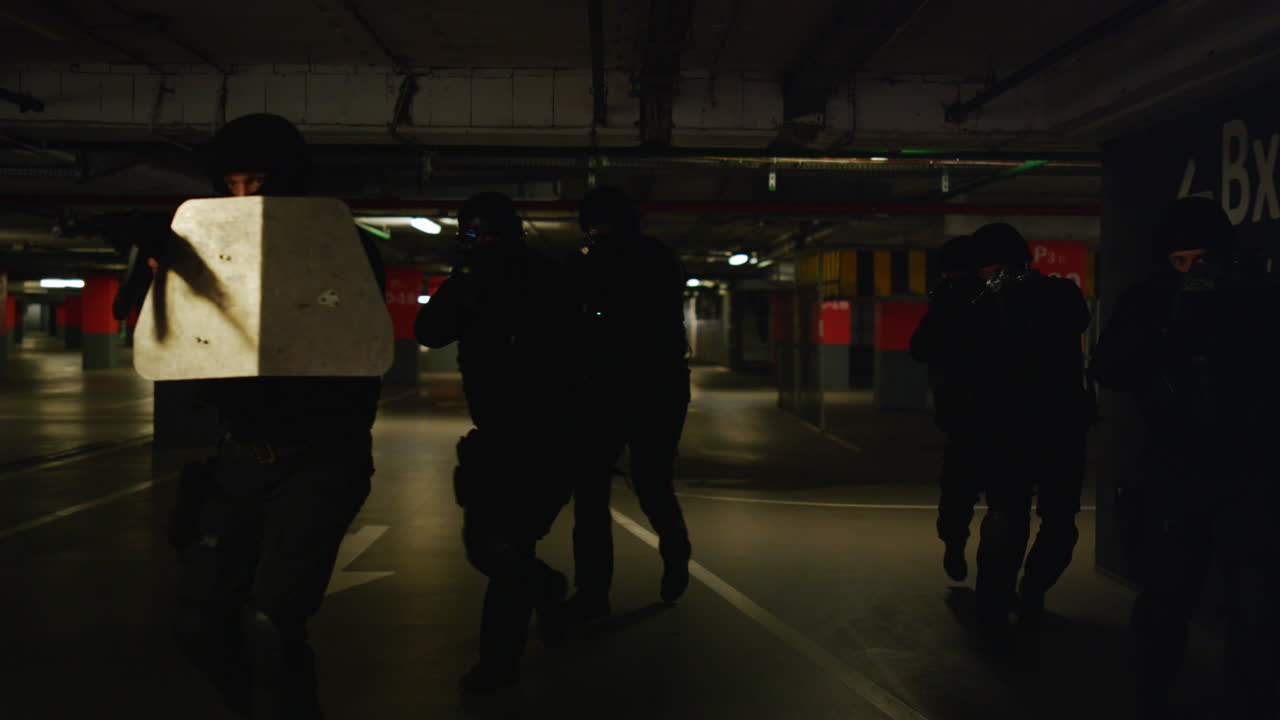 офицеры полиции swat прикрывают друг друга во время специальной операции.