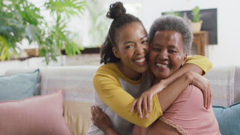 portrait of african american mother and daughter smiling while hugging each other at home