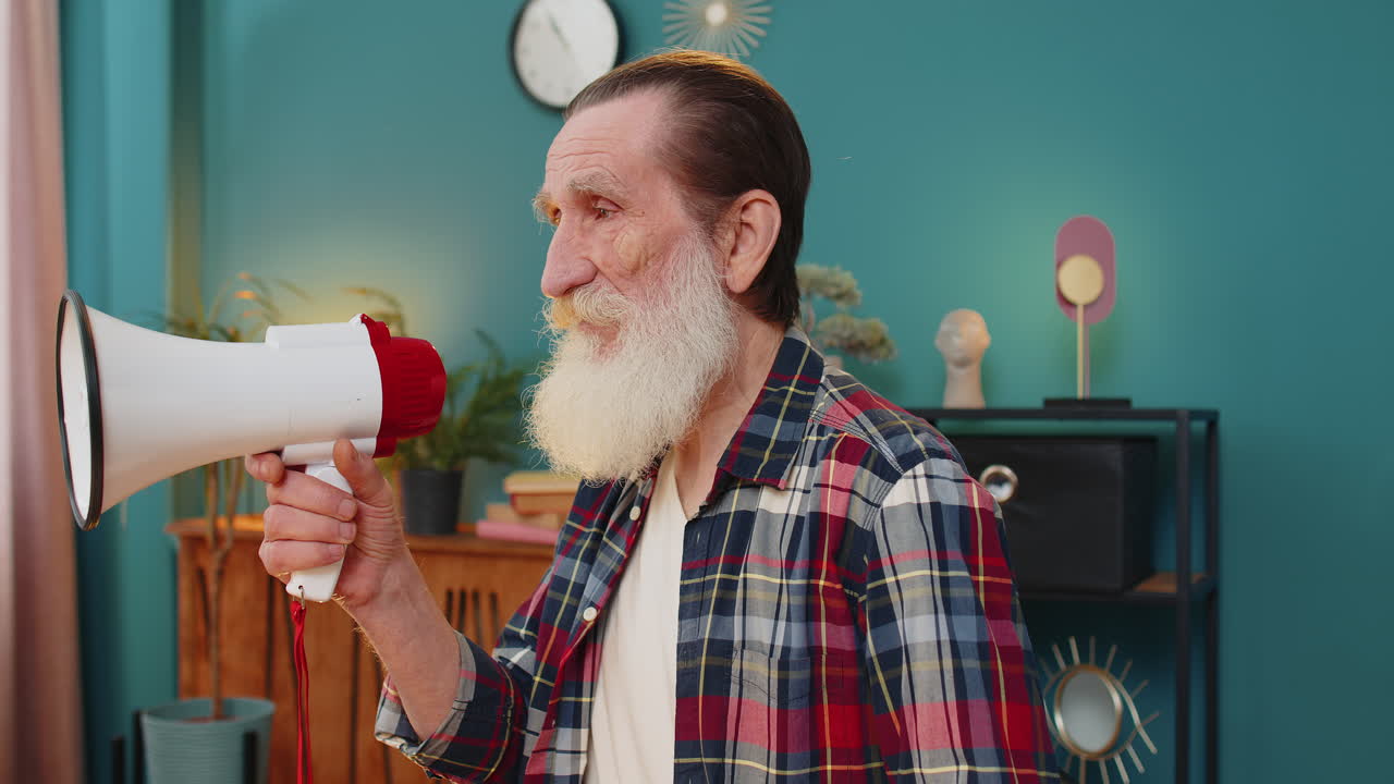 старший мужчина разговаривает с мегафоном, громко объявляет новости, объявляет рекламу в домашнем офисе.