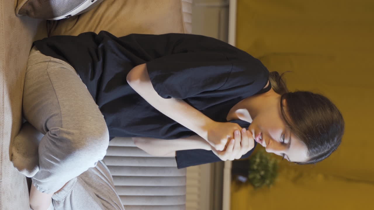 자리에 앉아서 긴장해서 흔들리는 젊은 여성의 수직 비디오.