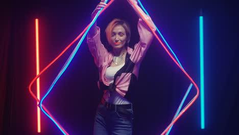 young woman with orange make up dancing in neon tubes light