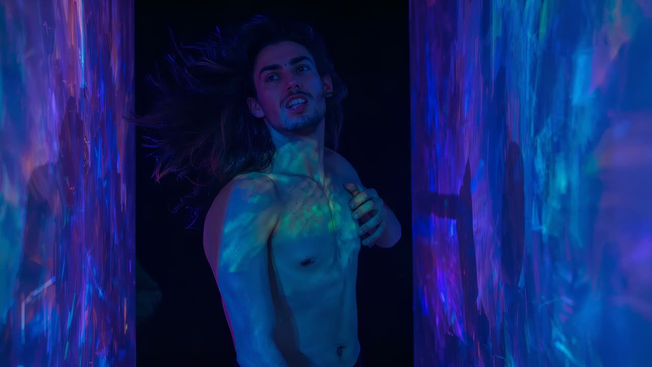 Uomo a torso nudo, inclinato, che sente la brezza, con la mano sul petto in uno scatto in studio con pannelli blu-viola
