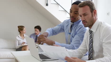 Close-on-two-businessmen-smiling-and-working-with-a-laptop