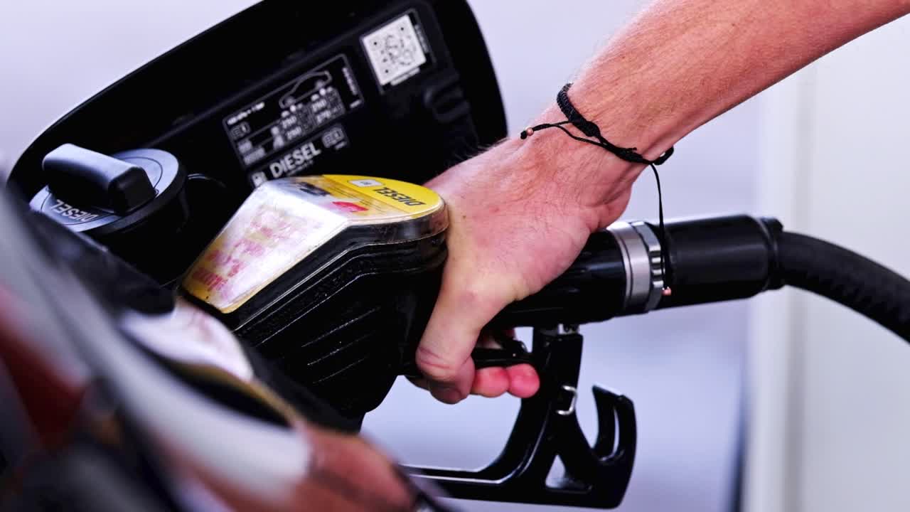 Un uomo usa una pompa di benzina per fare rifornimento alla sua auto.