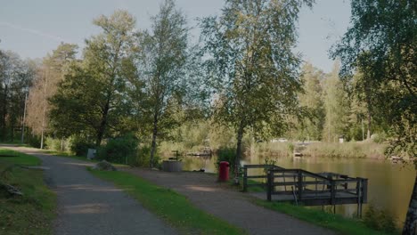 POV-Taking-a-Walk-By-Kypesjön-in-the-Late-Summer-Afternoon,-Borås-Sweden,-Wide-Shot-Tracking-Forward