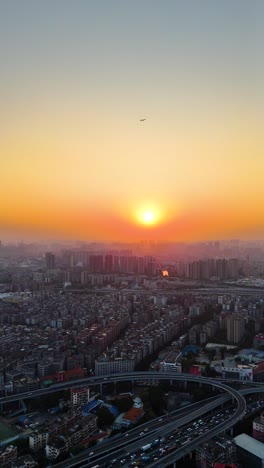 vertical aerial view of guangzhou cityscape at sunset, capturing the golden hues of the sky over the sprawling urban landscape, with the sun setting behind the city’s edge. china