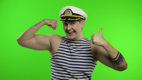 young sailor man shows muscles, looking at camera. seaman guy in sailor's vest