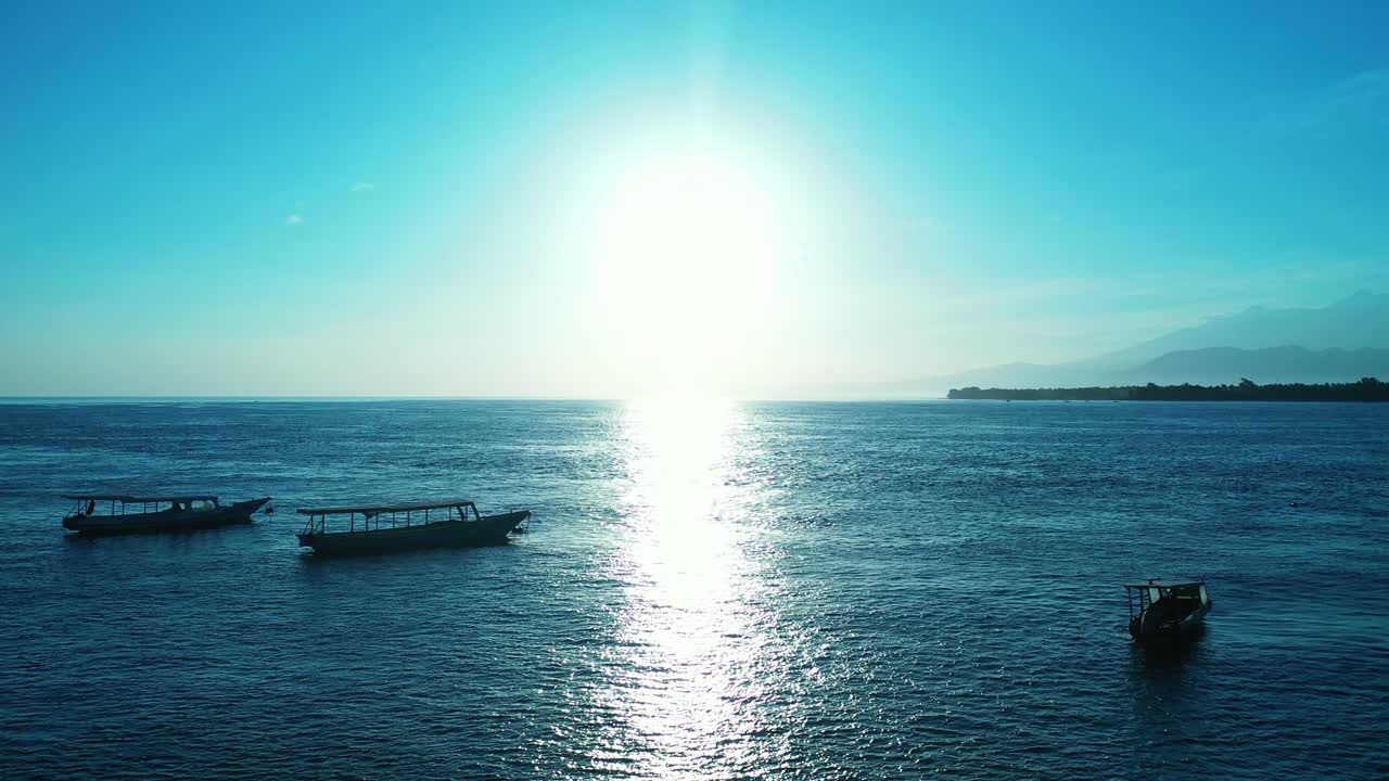 세 개의 작은 보트가 잔물결에 반사되는 아름다운 태양과 함께 밝은 푸른 물 표면에 앉아 있다