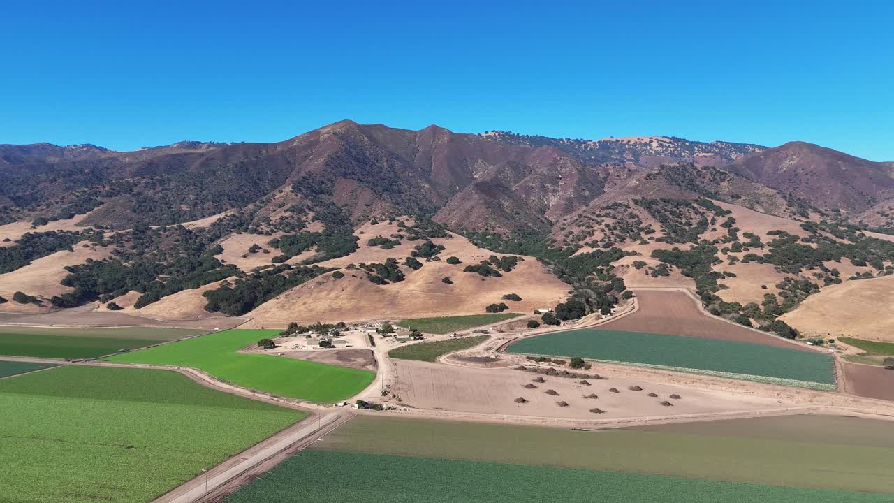Farmland With Colorful Crop Fields and Dirt Roads in Mountain Valley Landscape