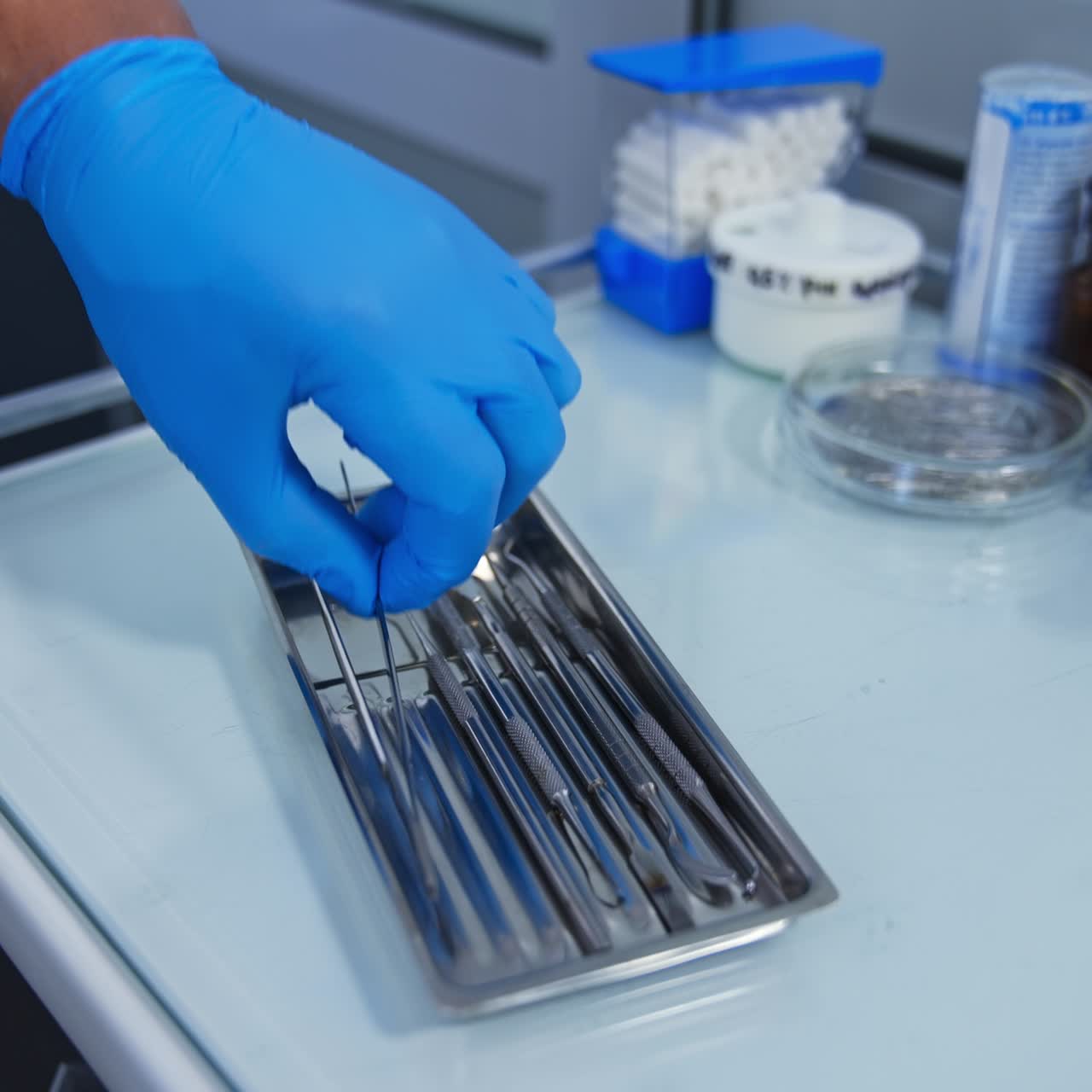 Chest of drawers with medical tools for dentistry. Hand in blue latex gloves picks one of the instrument. Close up