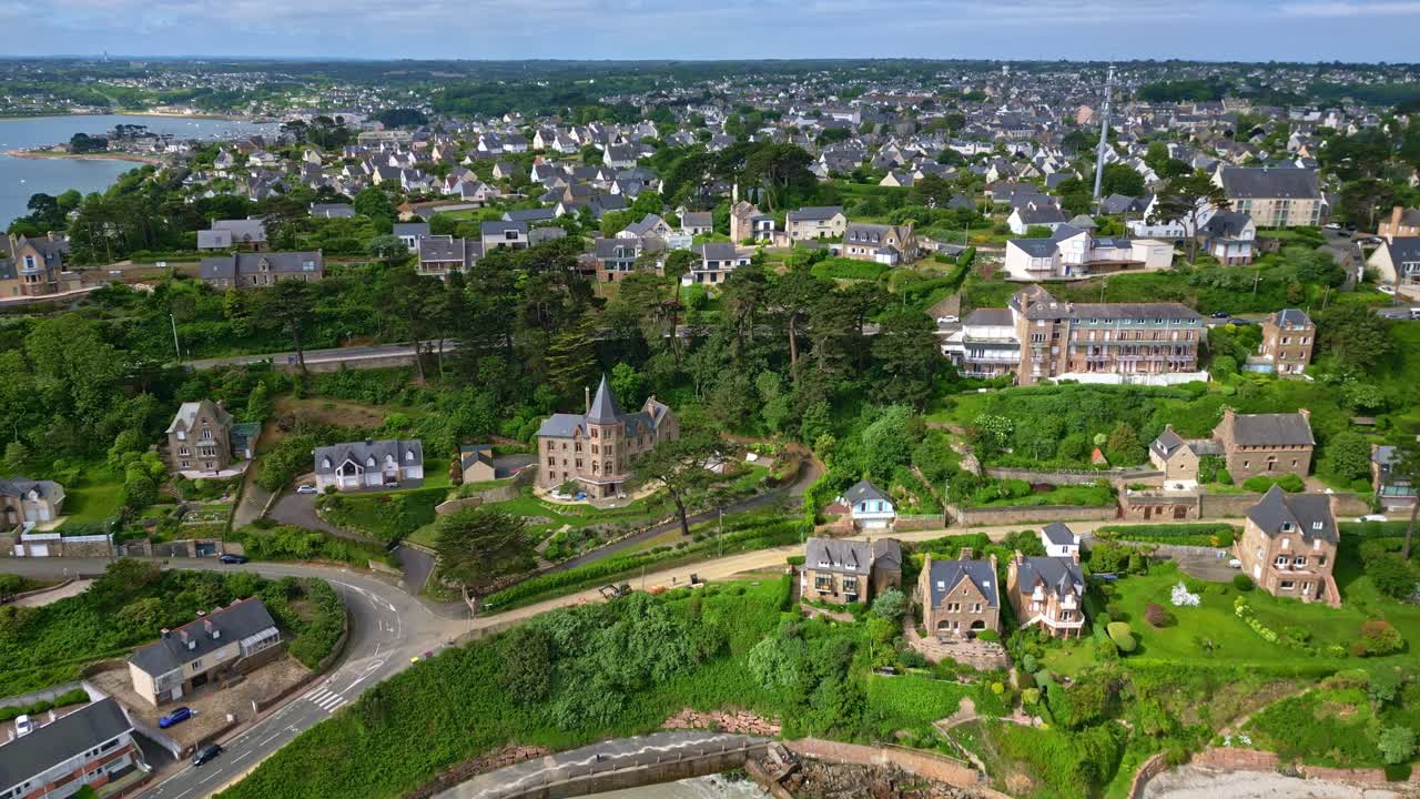 Plage de Trestignel beach and Perros-Guirec coastal town, historic houses on green hills, Brittany, France. Aerial drone forward