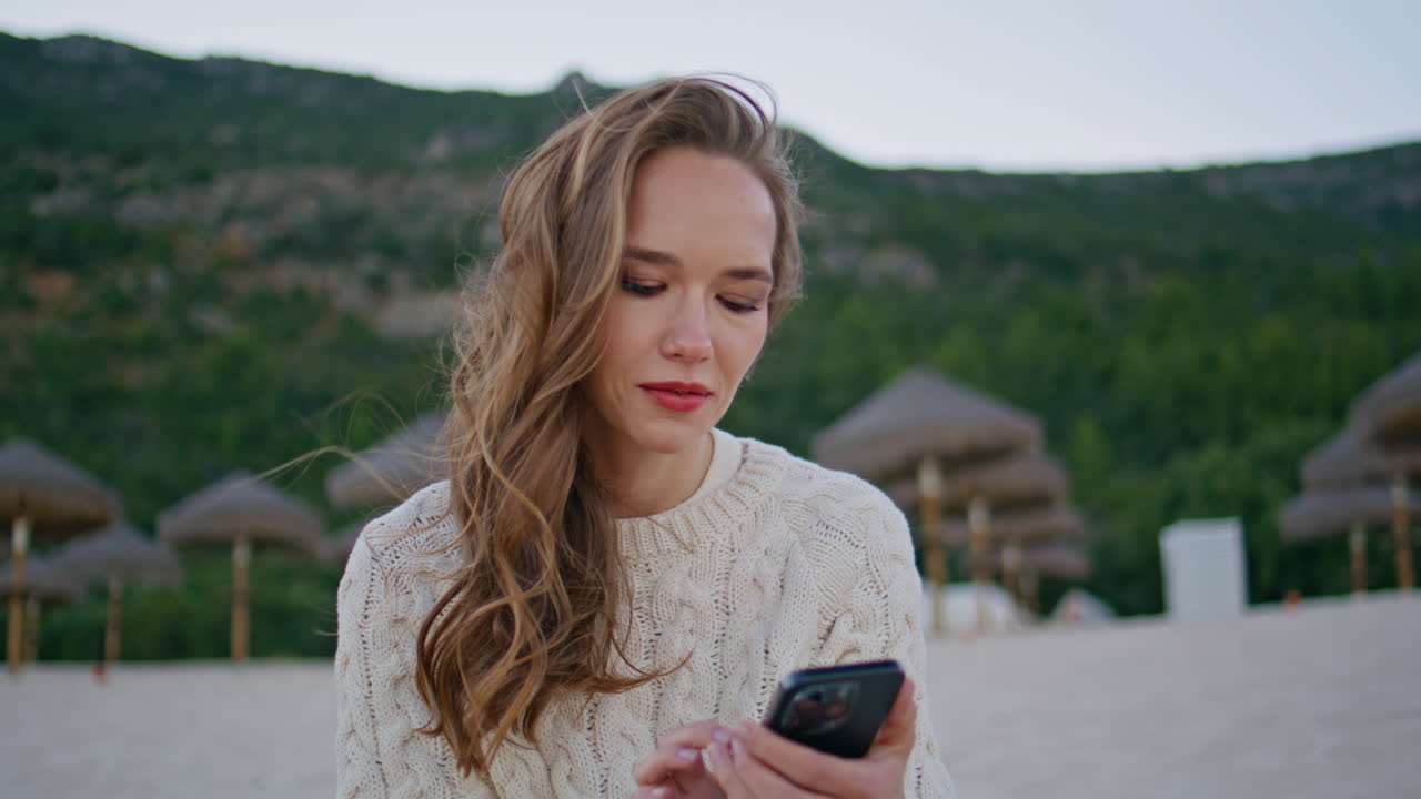 Traveler typing message ocean shore at windy morning closeup. Calm woman texting
