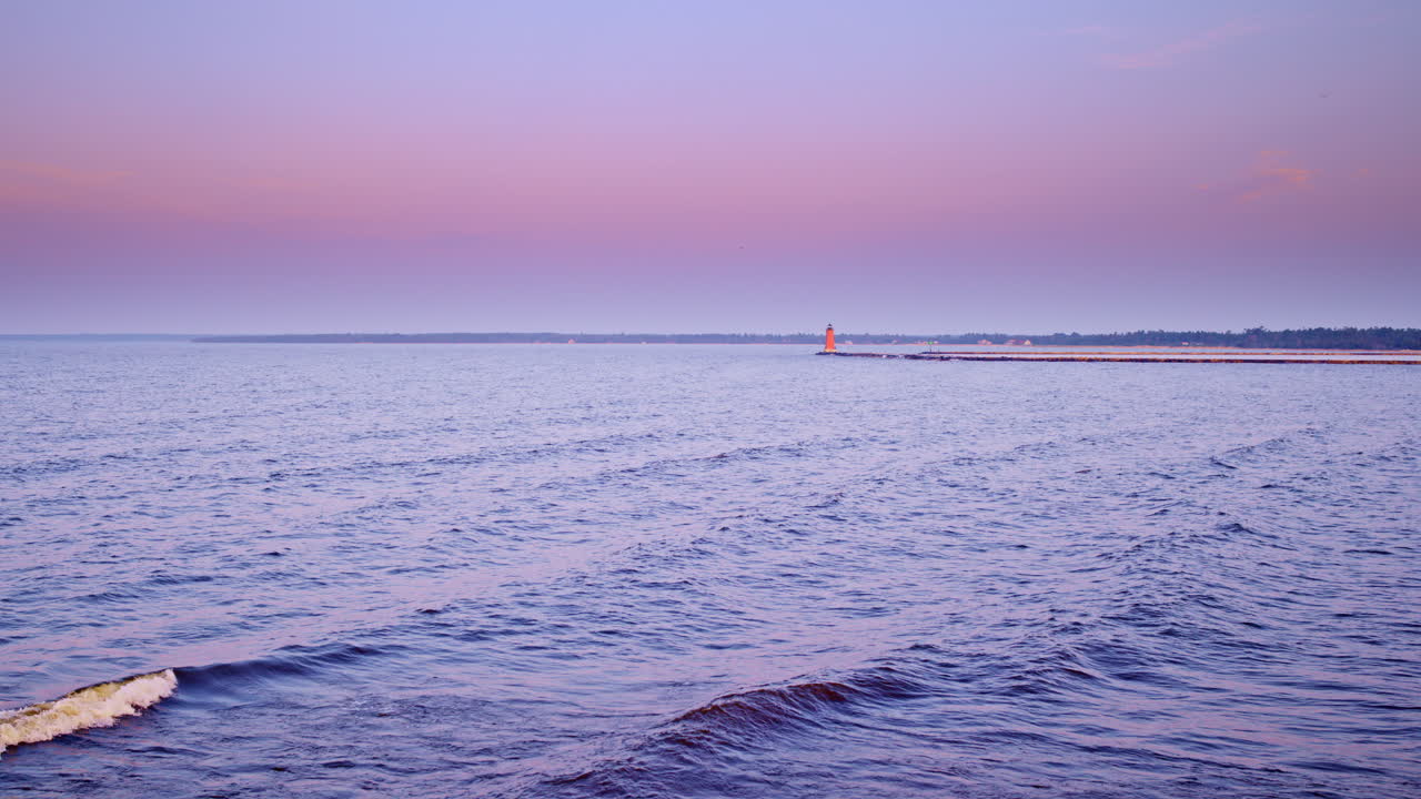 Drone shot flying from the shore of lake Michigan towards the breakwater and lighthouse near Manistique Michigan