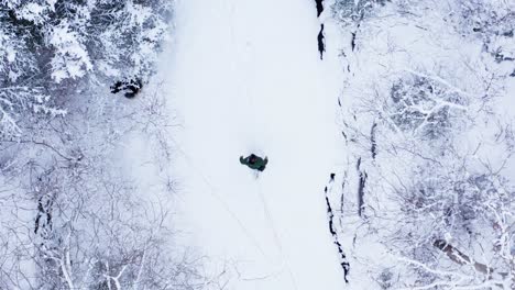 guy walking on deep snow forest with his dog