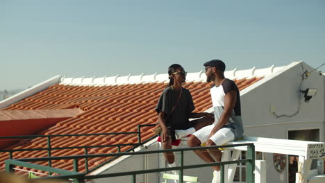 long shot of afro-american gays sitting on rooftop and talking