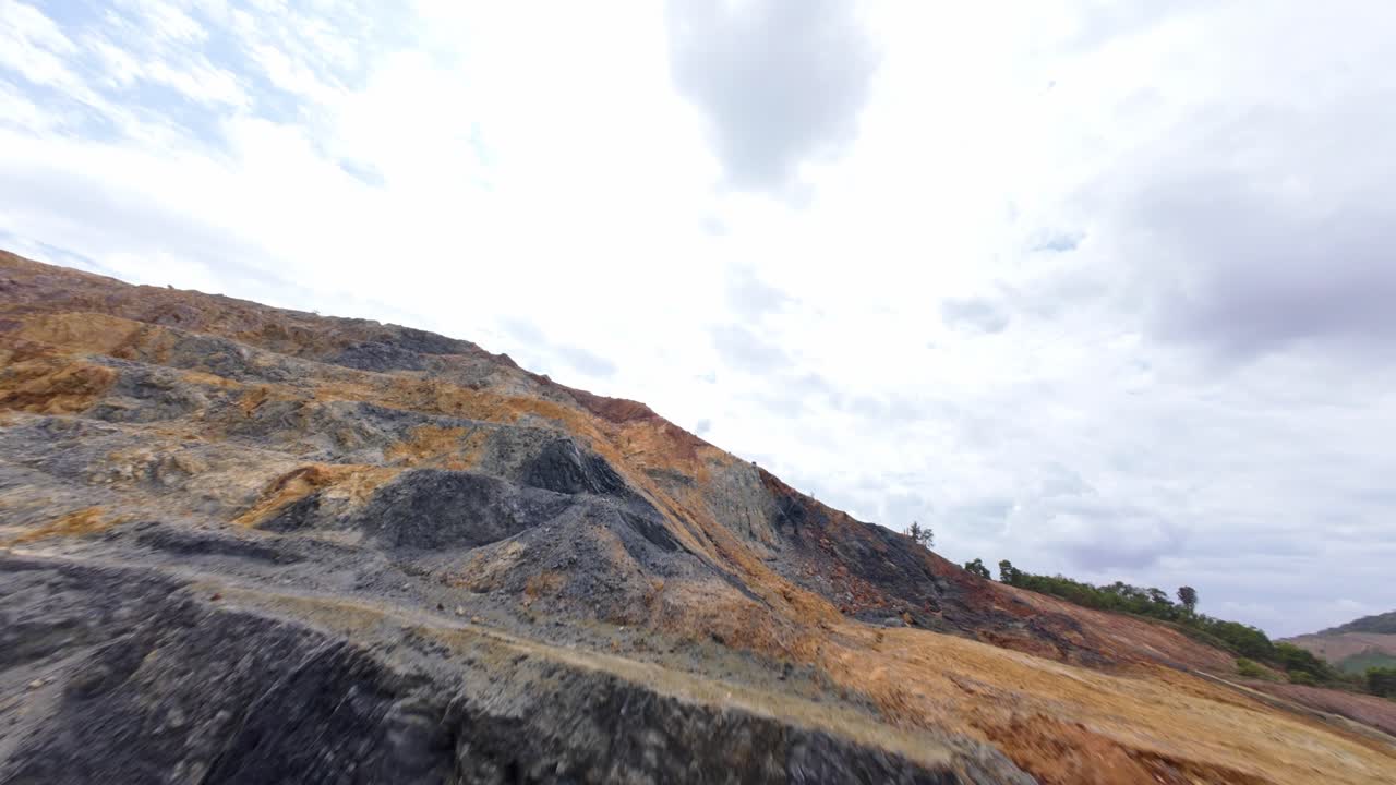 Fpv flight uphill gold and silver mine with factory on top of mountain. Cloudy day in Cotui, Dominican Republic. Storage Pipelines and rising steam.