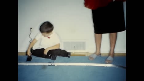woman and two children playing with toy train. circa usa - 1970s: a woman and two children in a 1970s video archive from the usa playing with a toy train.