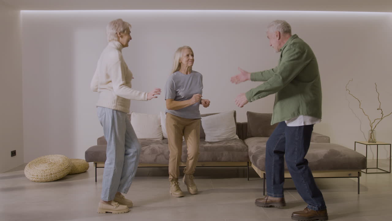 Tre anziani amici felici che ballano insieme a casa 1