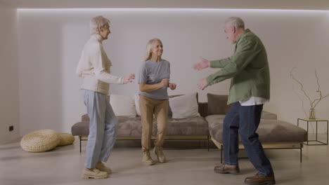 three happy senior friends dancing together at home 1