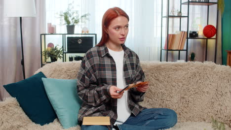 woman sitting on sofa counting cash euro putting part into envelope looking happy and satisfied