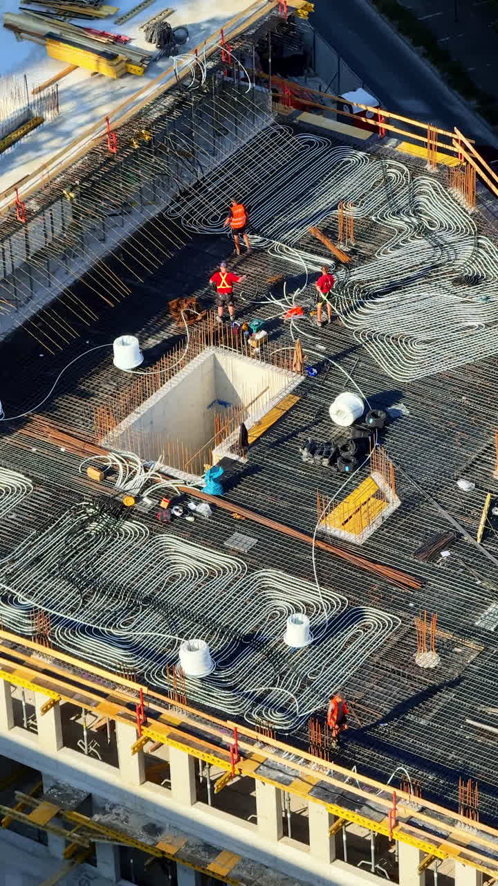 Roof framework being built. Workers lay rebar and insulation on a rooftop during the day to ensure the building's integrity
