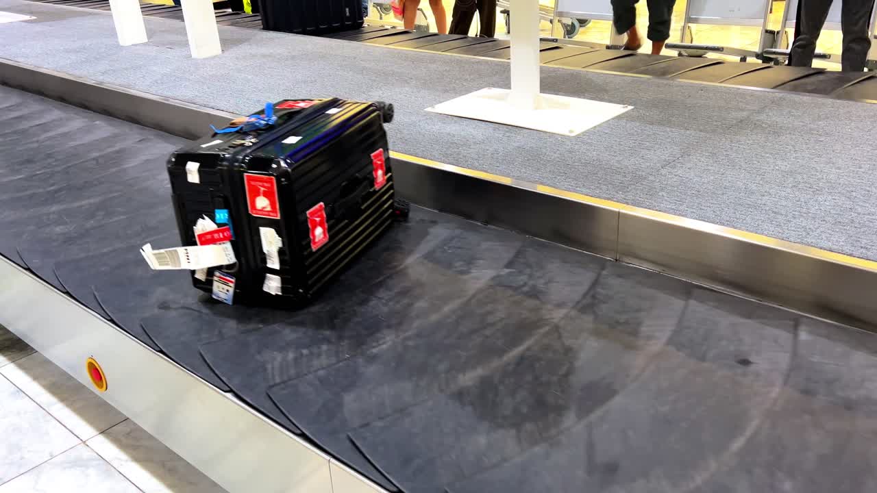 Black suitcase with red fragile stickers on an airport baggage carousel, perfect for travel, tourism, airline, and transportation-themed media projects